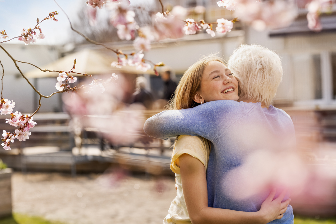 äldre kvinna kramar barnbarn